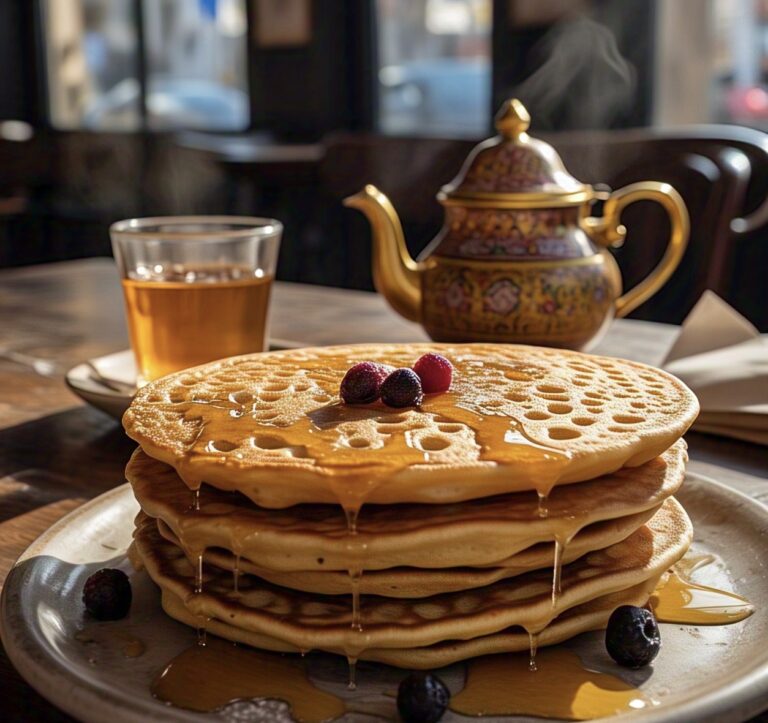 A stack of baghrir pancakes drizzled with honey and butter.
