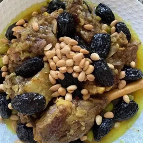 A traditional Moroccan lamb tagine served in a clay pot with prunes, almonds, and aromatic spices.