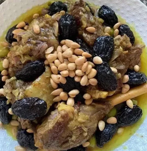 A traditional Moroccan lamb tagine served in a clay pot with prunes, almonds, and aromatic spices.