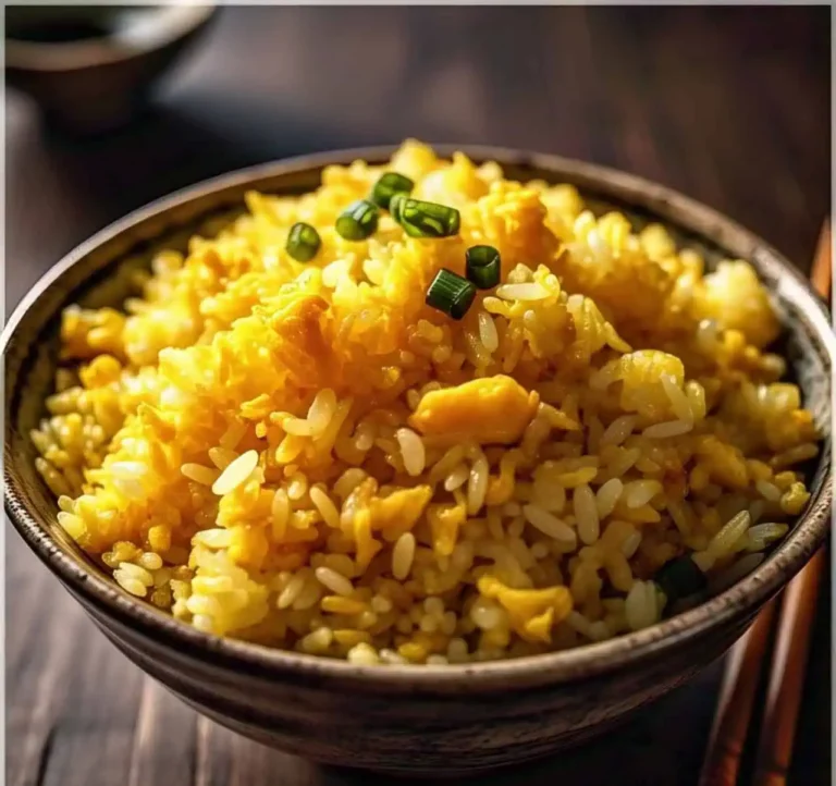 A bowl of golden fried rice with egg yolk coating each grain.