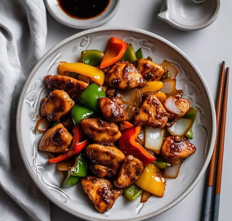 A plate of Black Pepper Chicken stir-fry with bell peppers and onions served over steamed rice.