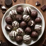 A plate of homemade Oreo truffles coated in chocolate with a drizzle on top.