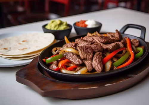 A sizzling cast-iron skillet filled with steak fajitas, sautéed peppers, and onions.