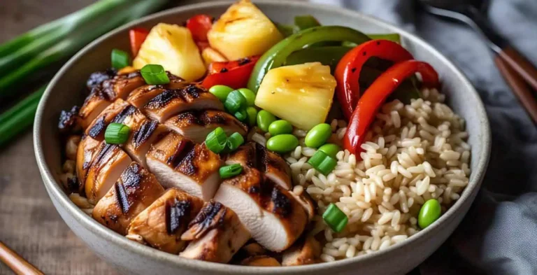 Overhead view of teriyaki chicken and rice bowl with grilled pineapple, peppers, and edamame